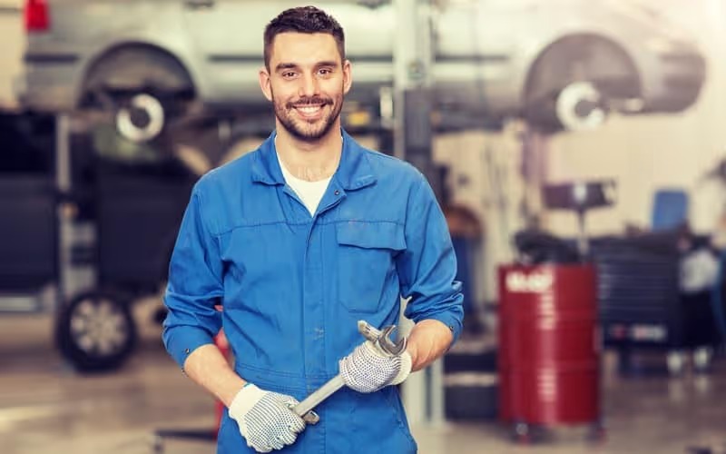 Mechanic smiling and holding a wrench while working on plumbing truck repair near me