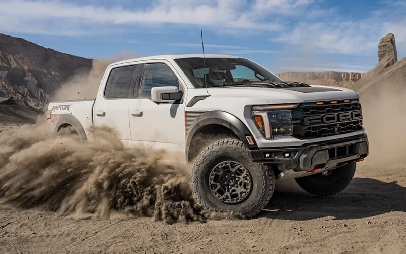 Pre-owned Ford F-150 Raptor driving while kicking up dirt from used car dealer near Brandon FL