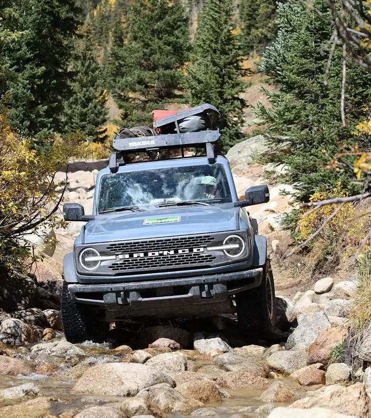 A 2025 Ford Bronco SUV driving on a rocky trail.