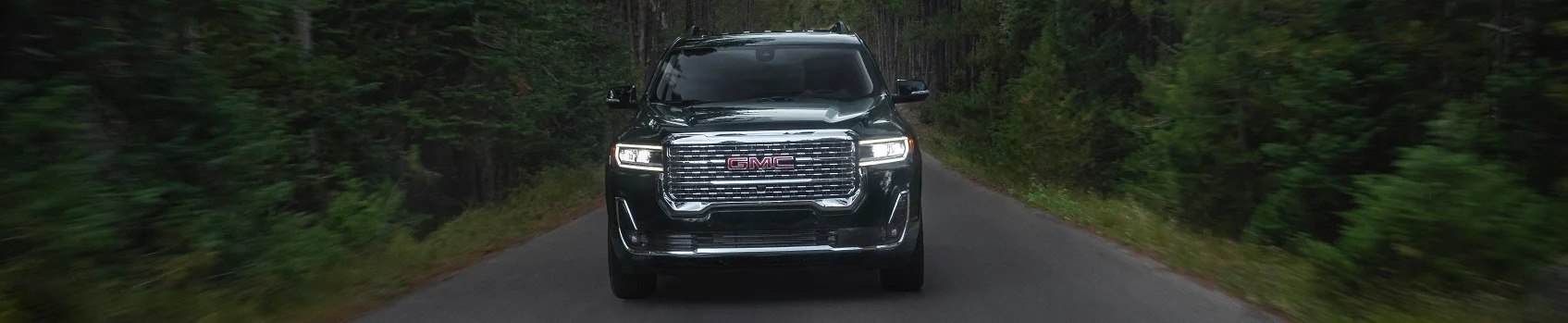 GMC Denali driving through a forest road
