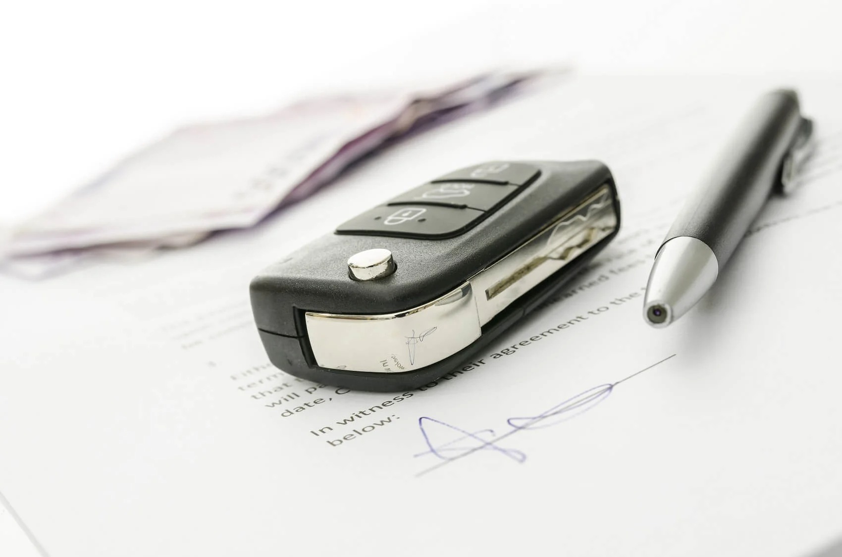 Car keys on top of financing papers and pen