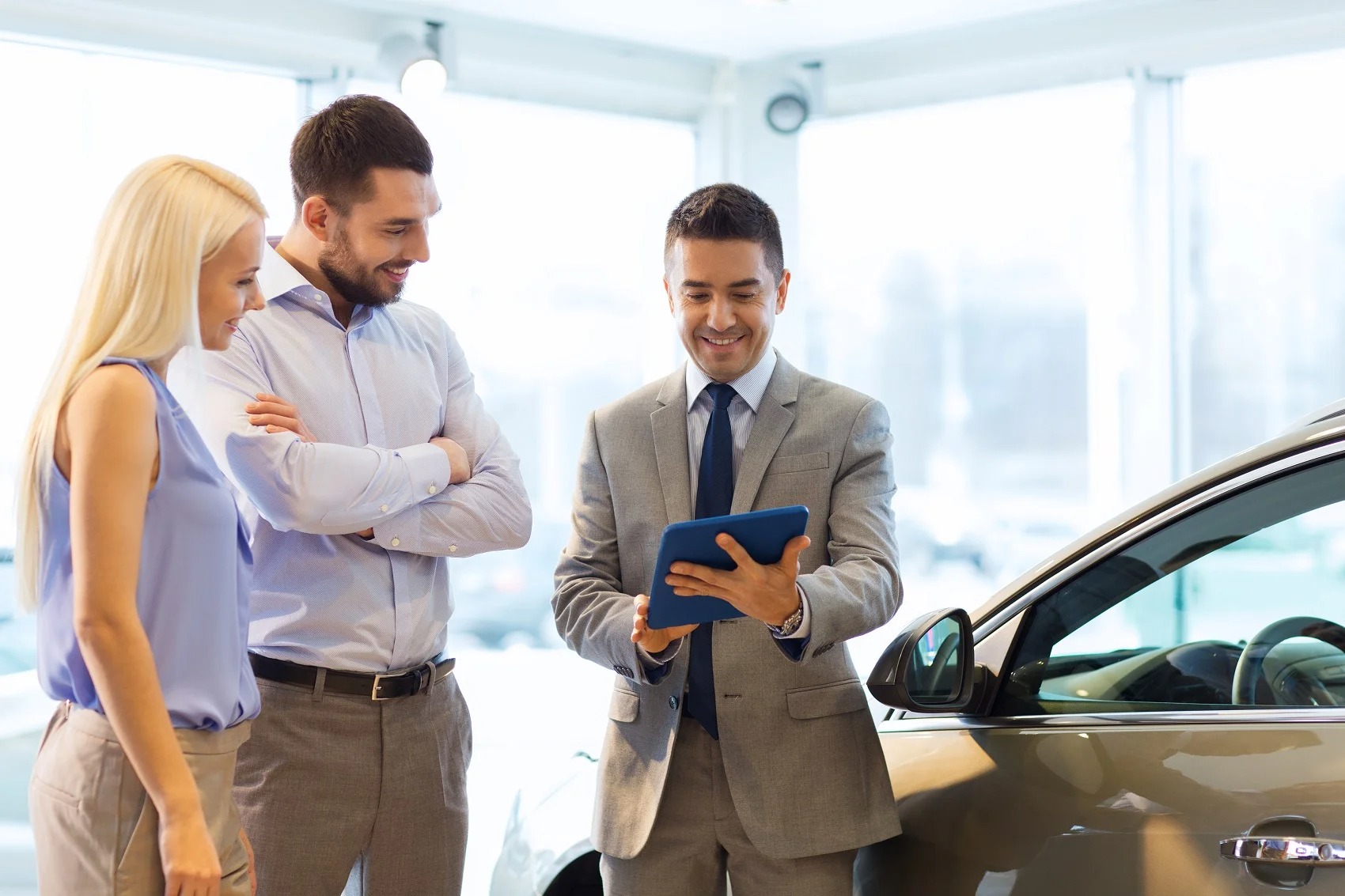 Sales manager talking to a couple in dealership showroom