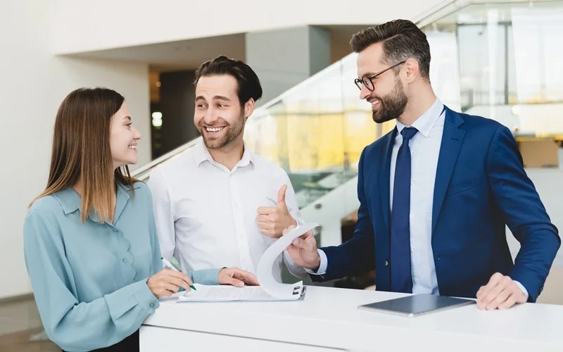 Finance manager talking to couple while signing paperwork