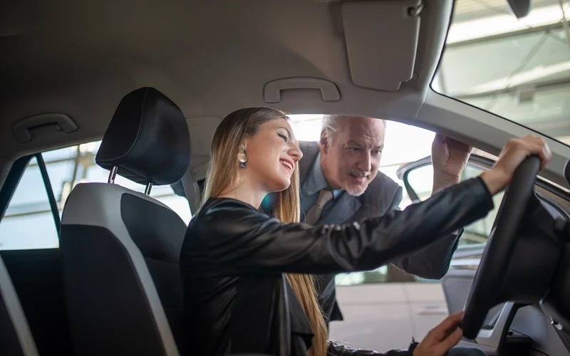Key fob being held in front of a used car lineup