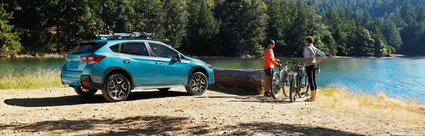 Subaru parked by a lake with a roof bike rack, two people with bikes nearby, Affirm logo