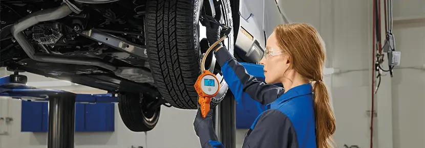A Subaru technician checking tire pressure