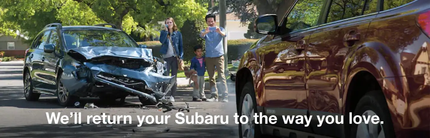 A damaged Subaru with safe and unharmed occupants standing by the vehicle